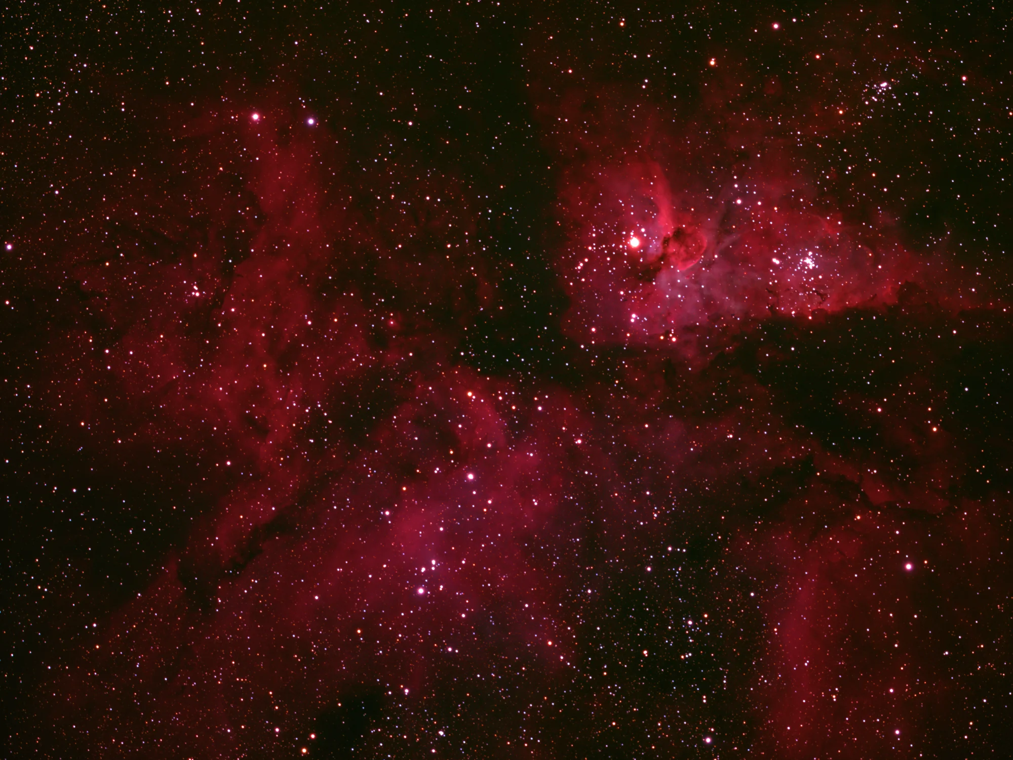 The Carina Nebula glowing in red, violet and blue among a dense star field
